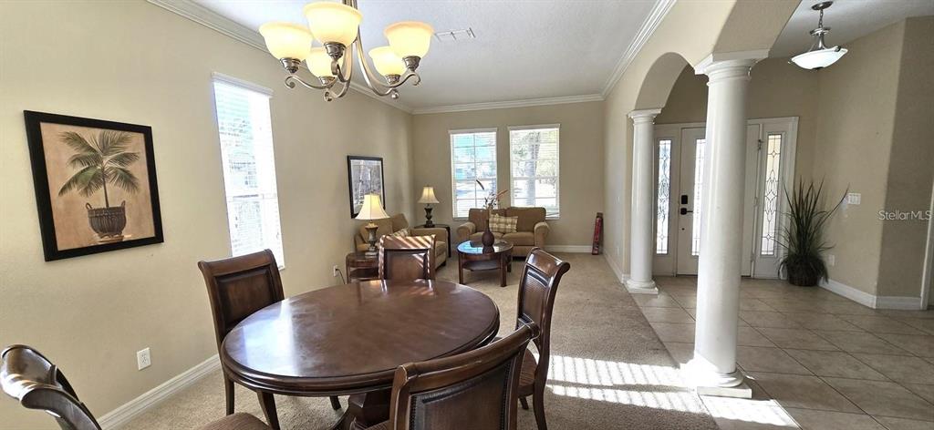 A dining area with a round wooden table and chairs sits adjacent to a living room — 844 SUFFOLK PLACE, DAVENPORT, FL