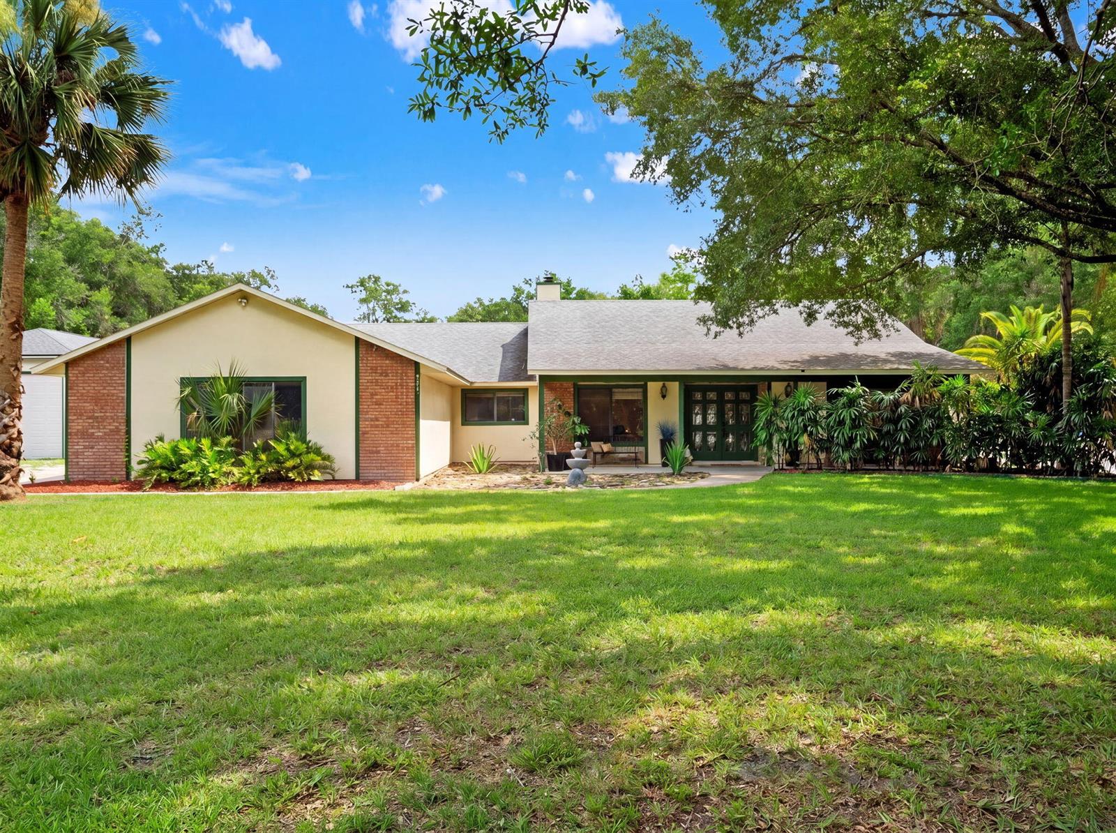 A single-story house with a brick and stucco exterior sits behind a large green lawn — 3501 Hill Stream Avenue, FL 32712, FL