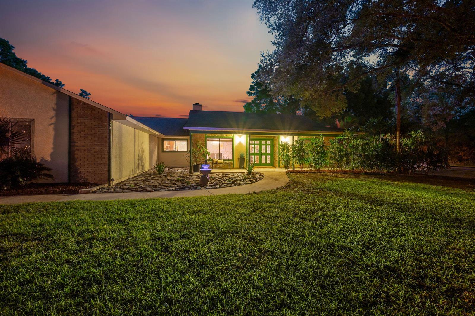 A single-story house with a brick and stucco exterior at dusk with a landscaped yard — 3501 Hill Stream Avenue, FL 32712, FL