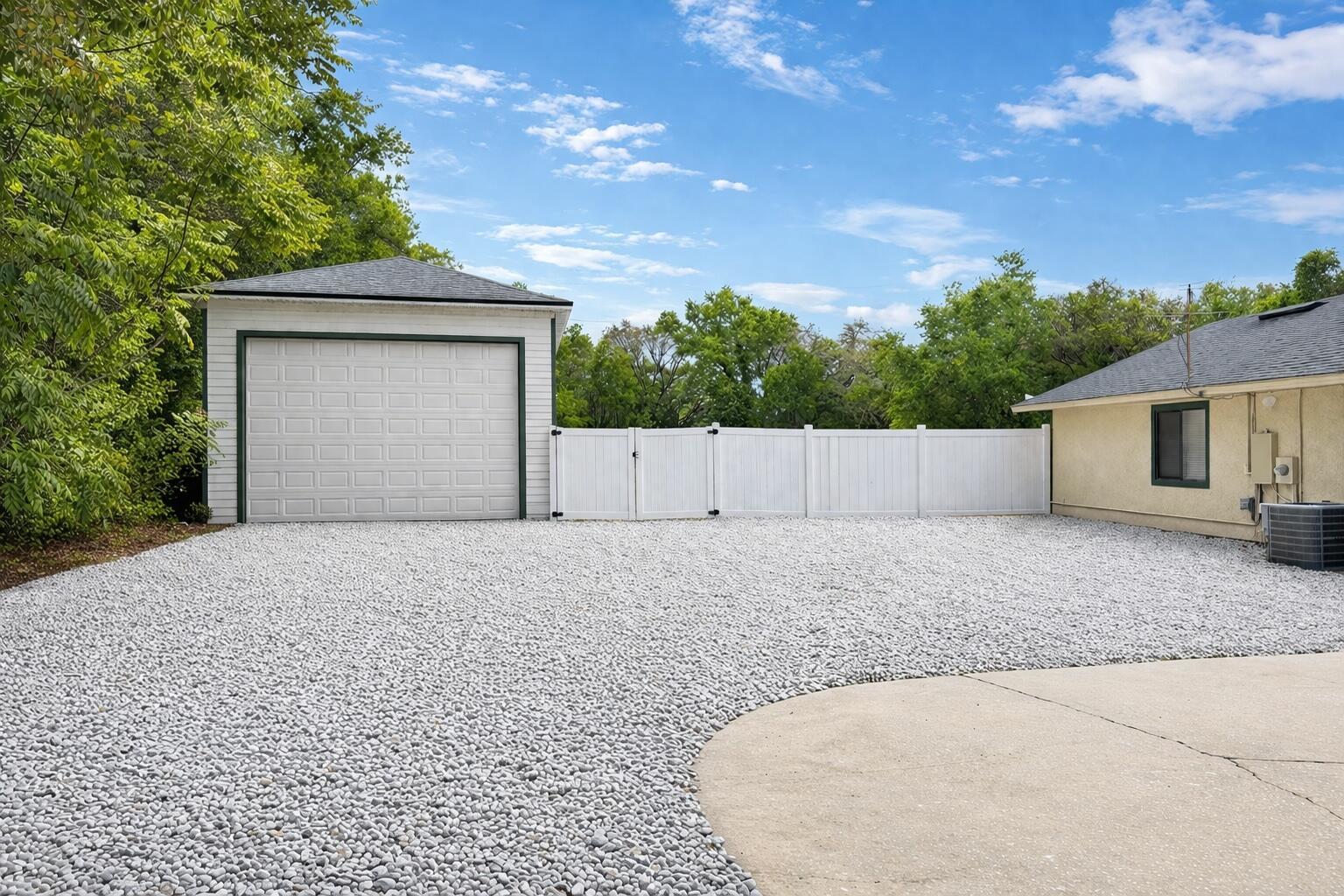 A detached garage and a house exterior are separated by a white vinyl fence — 3501 Hill Stream Avenue, FL 32712, FL