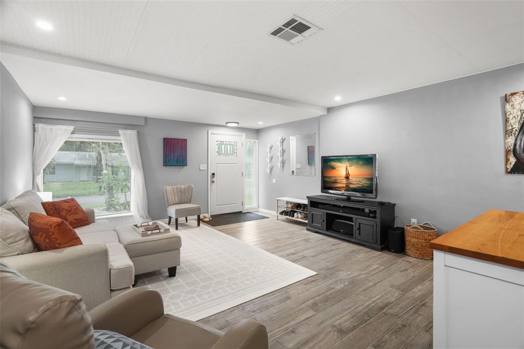 A living room with light gray walls, wood-look tile flooring, and a white front door — 1663 SAN MATEO DRIVE, DUNEDIN, FL