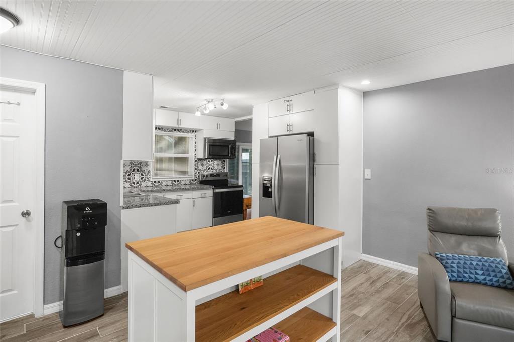 A kitchen features white cabinets, a wooden island, stainless steel appliances, and gray walls — 1663 SAN MATEO DRIVE, DUNEDIN, FL