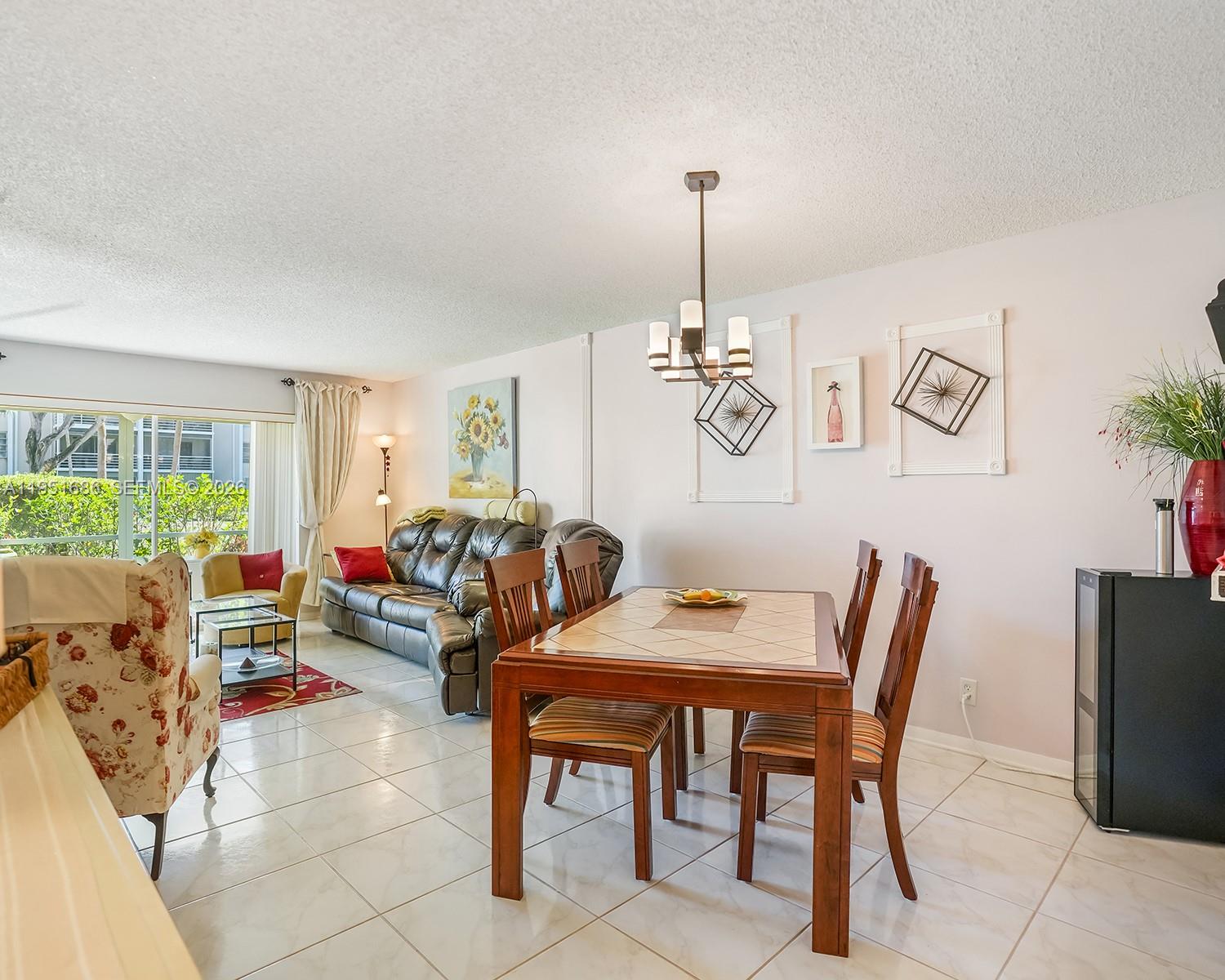 A dining area with a wooden table and chairs sits adjacent to a living room — 3531 Inverrary Dr # 107, Lauderhill FL 33319, LAUDERHILL, FL