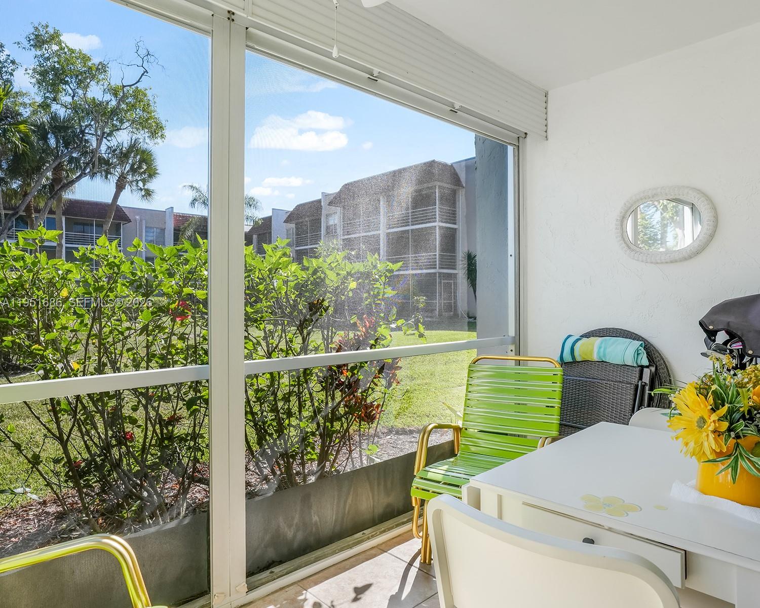 A screened-in patio features white walls, tile flooring, patio furniture, and a view of landscaping — 3531 Inverrary Dr # 107, Lauderhill FL 33319, LAUDERHILL, FL