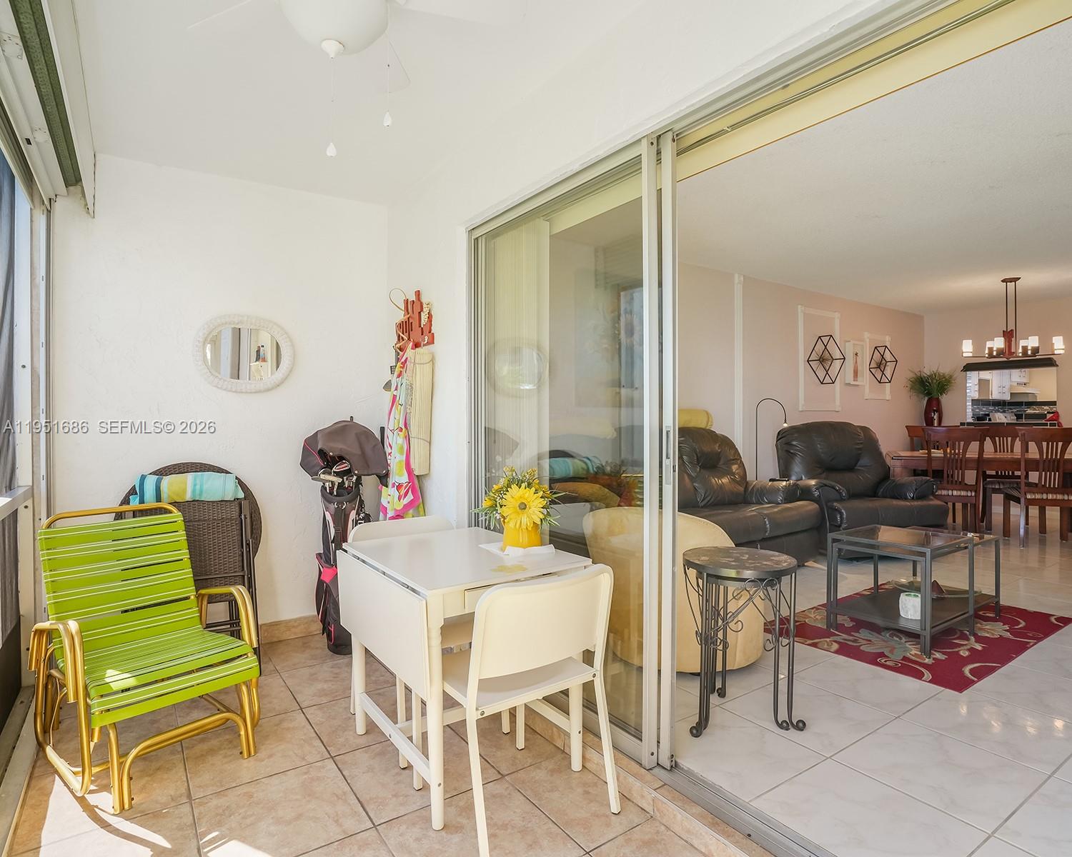 A sunroom with tile flooring and a small dining set opens into a living room — 3531 Inverrary Dr # 107, Lauderhill FL 33319, LAUDERHILL, FL