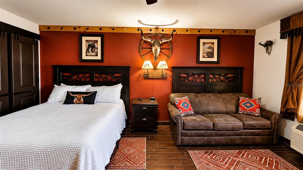 A bedroom features a bed, a brown sofa, and a steer skull wall decoration — 3200 RIVER RANCH BOULEVARD UNIT 170, RIVER RANCH, FL