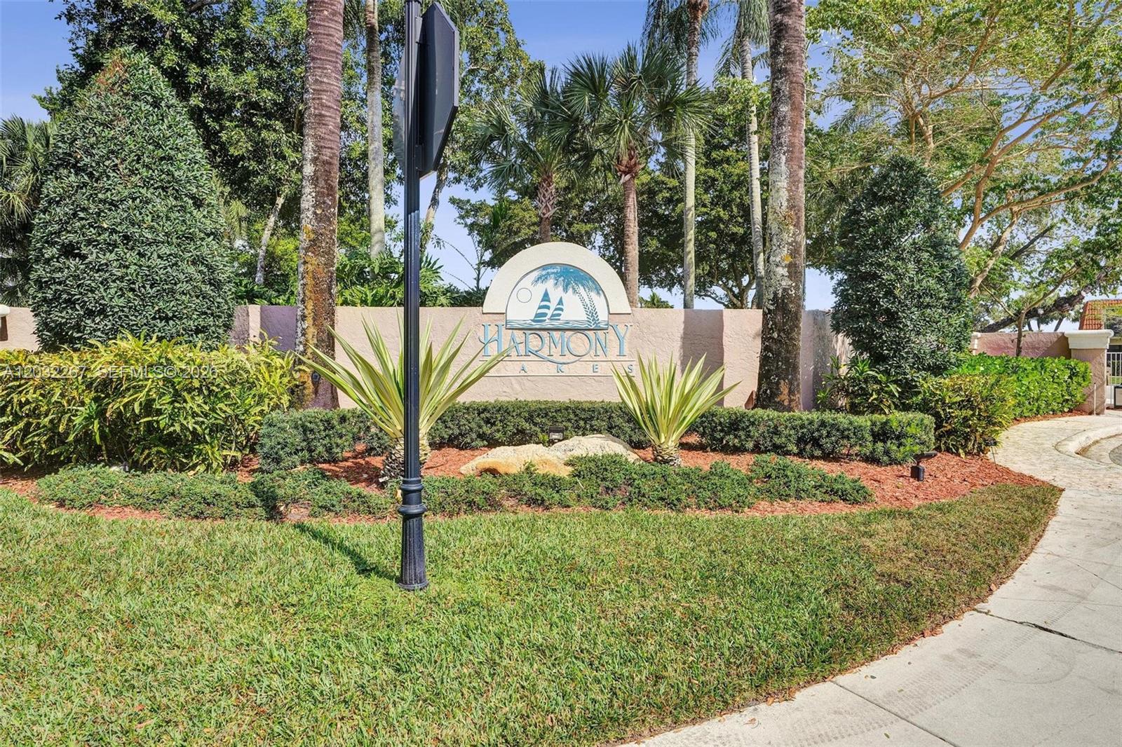 A stone monument sign for Harmony Lakes stands in a landscaped garden with palm trees — 11100 SW 15th Mnr, Davie FL 33324, DAVIE, FL