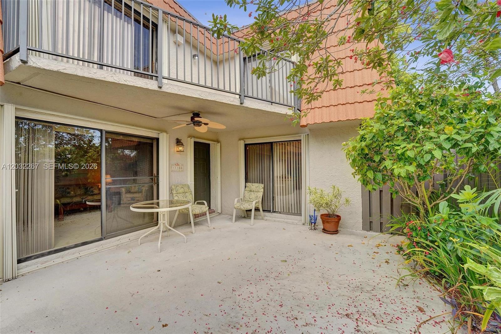 A concrete patio features a ceiling fan, two sliding glass doors, and a small garden — 11100 SW 15th Mnr, Davie FL 33324, DAVIE, FL