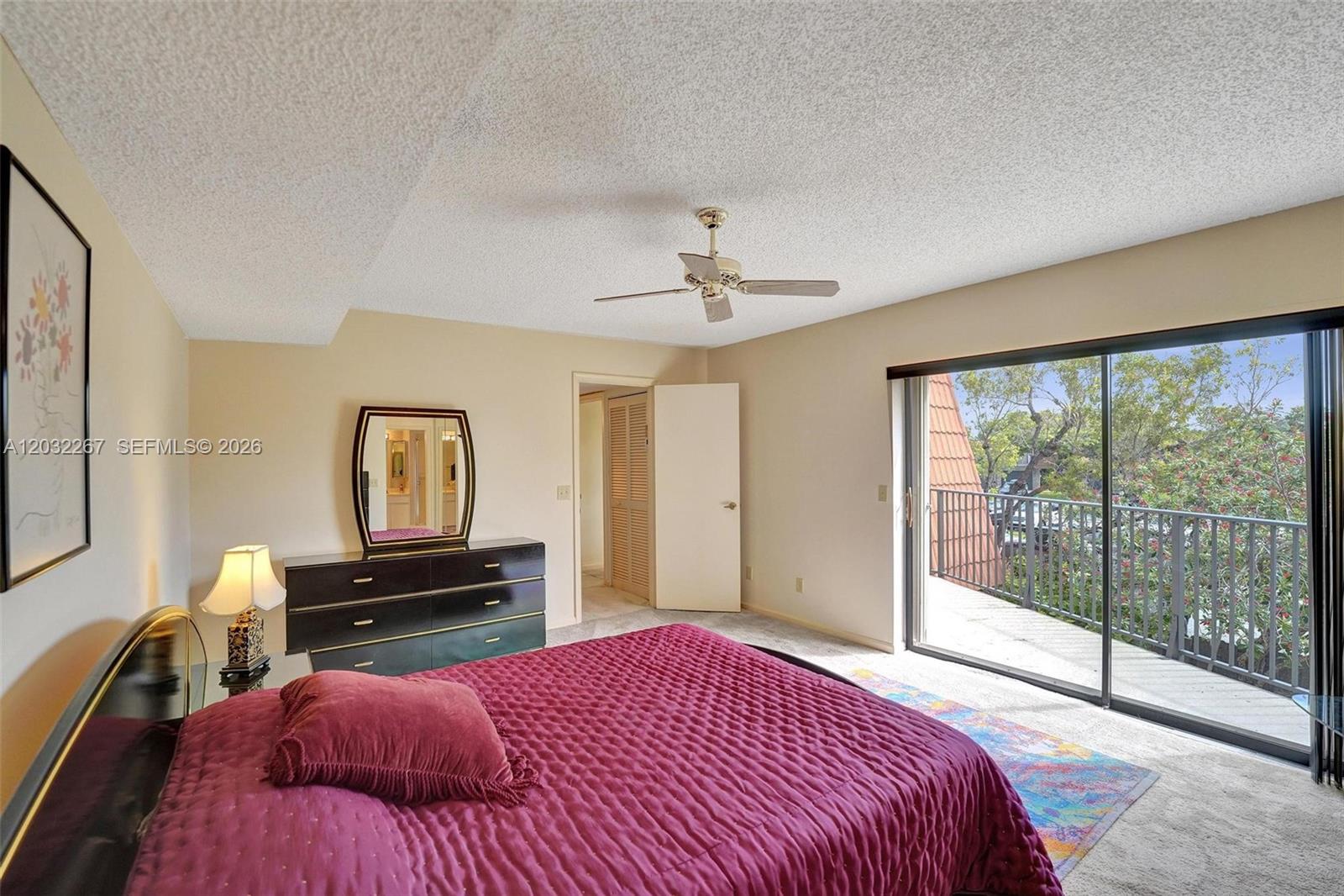 A bedroom features a magenta bedspread, a dresser with a mirror, and a sliding glass door — 11100 SW 15th Mnr, Davie FL 33324, DAVIE, FL