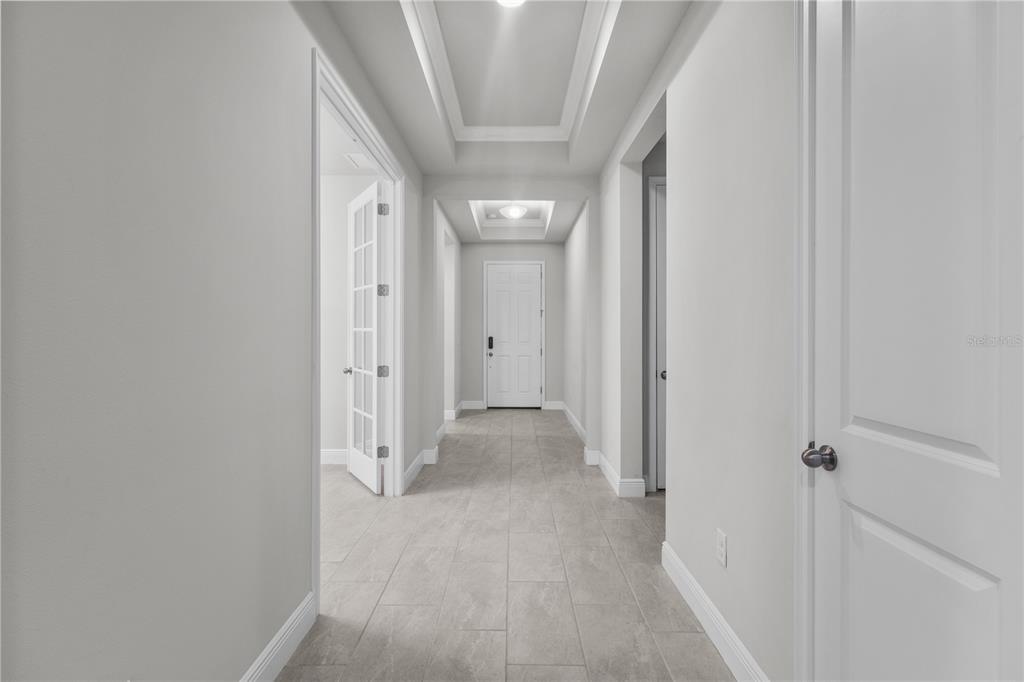 A bright hallway features light tile flooring, white walls, and a recessed tray ceiling — 8712 BAY MEADOW DRIVE, SARASOTA, FL