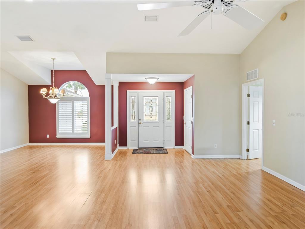 A spacious living area features hardwood floors, a red accent wall, and a white front door — 1870 NW 56TH TERRACE, OCALA, FL