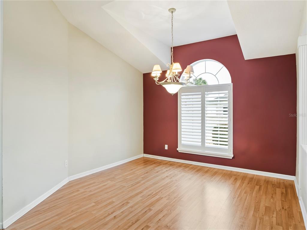 An empty dining room features hardwood floors, a vaulted ceiling, and a red accent wall — 1870 NW 56TH TERRACE, OCALA, FL