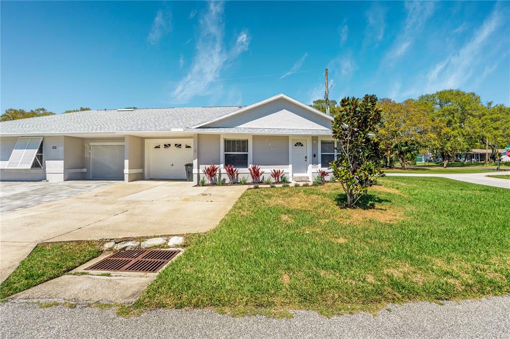 A single-story duplex with a concrete driveway, a garage, and a grassy front yard — 710 RIVER OAKS CIRCLE, NEW SMYRNA BEACH, FL
