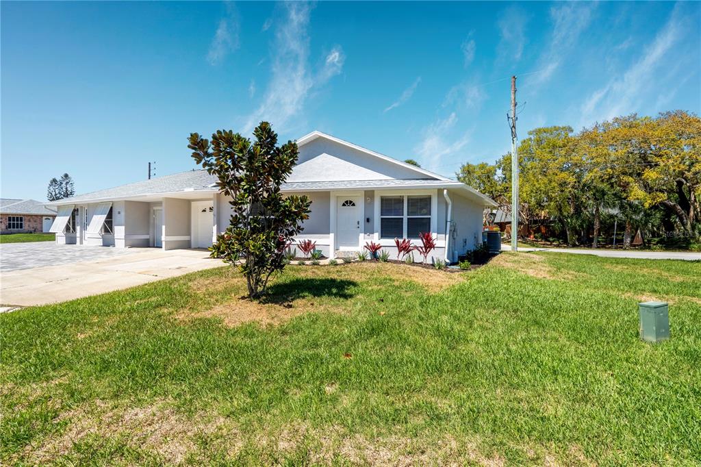 A single-story duplex with a white exterior, a front lawn, and a paved driveway — 710 RIVER OAKS CIRCLE, NEW SMYRNA BEACH, FL