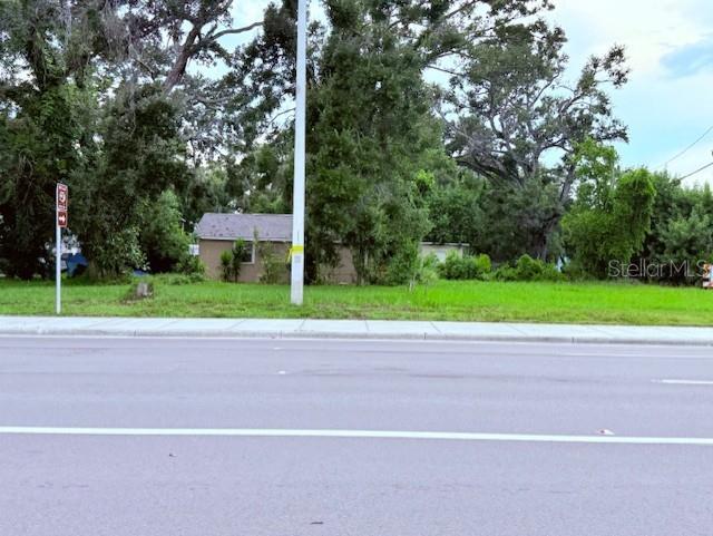 A small house sits behind a grassy lot next to a road with a utility pole — 3415 21ST AVENUE S, ST PETERSBURG, FL