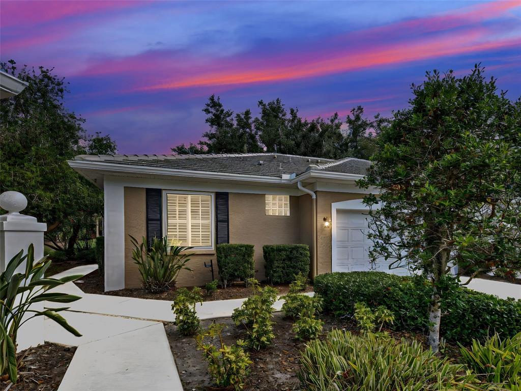A single-story house exterior with a tan facade, white trim, and a concrete walkway at dusk — 912 BARCLAY COURT, VENICE, FL