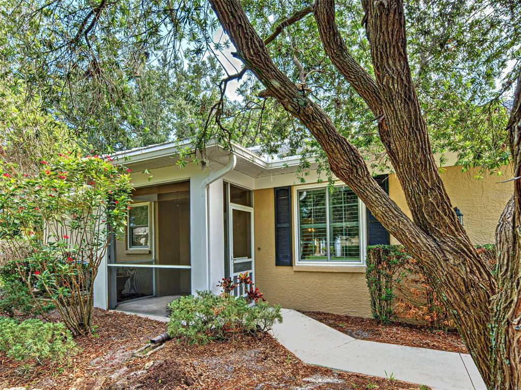 A concrete walkway leads to the screened-in porch and front entrance of a stucco house — 912 BARCLAY COURT, VENICE, FL