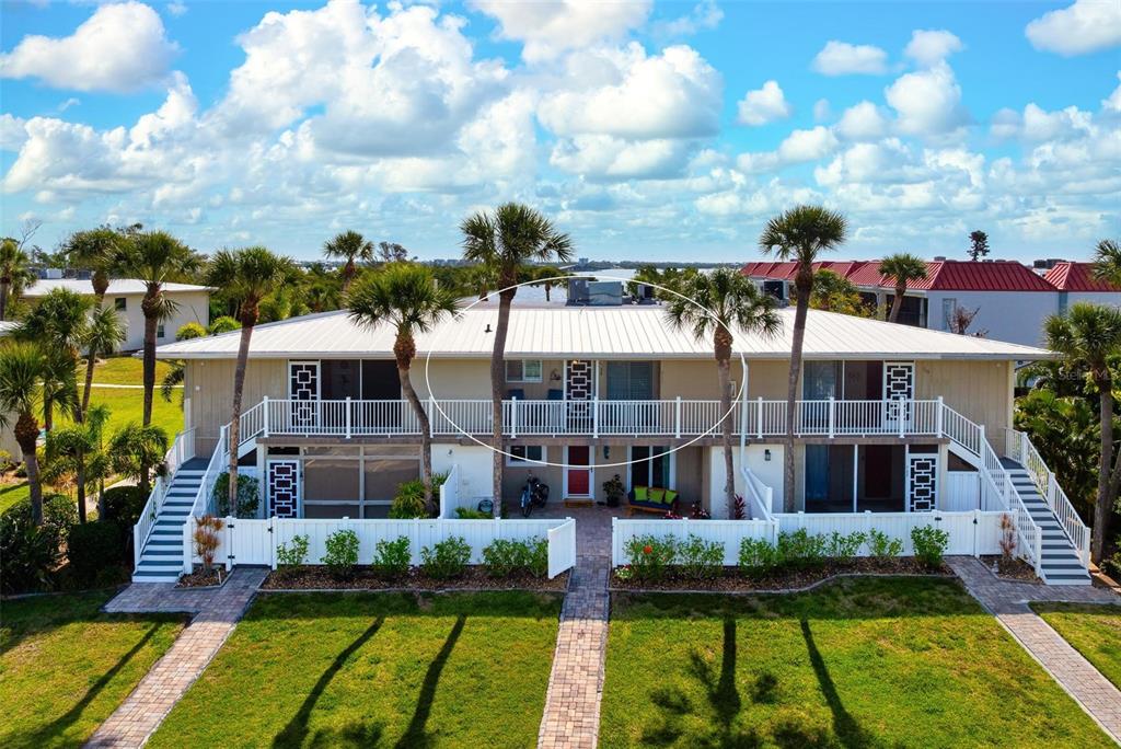 An exterior view of a two-story residential building with a white balcony and palm trees — 711 MANATEE AVENUE, HOLMES BEACH, FL