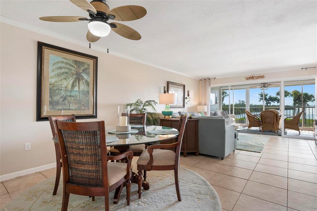 A dining area with a glass table and wicker chairs opens into a living room — 711 MANATEE AVENUE, HOLMES BEACH, FL