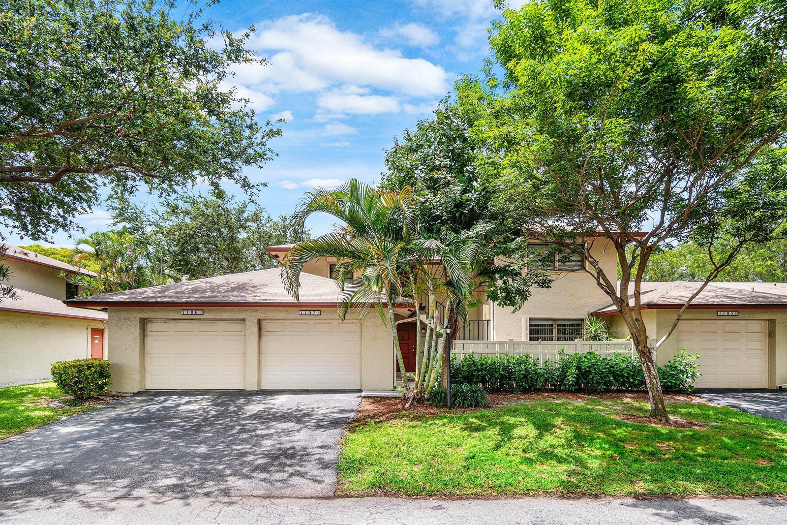 A two-story townhouse exterior features a two-car garage, a palm tree, and mature landscaping — 1779 NE 39th Court # 1106, Pompano Beach FL 33064, POMPANO BEACH, FL