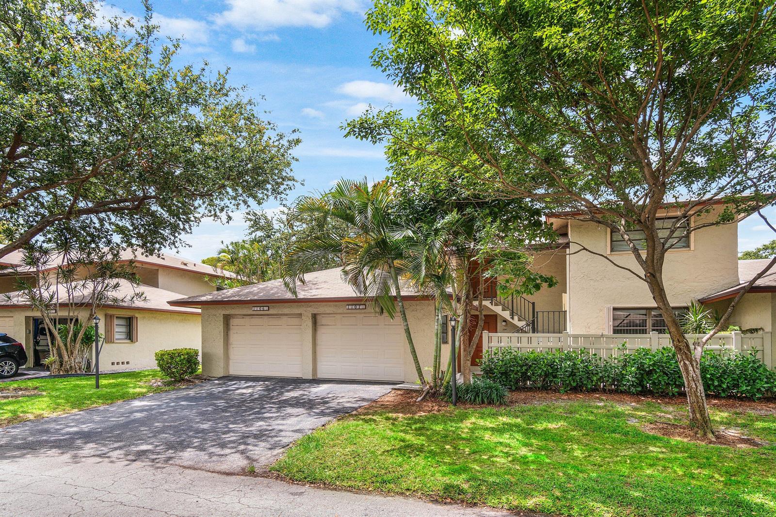 A two-story residential building features two garage doors, a driveway, and surrounding trees and landscaping — 1779 NE 39th Court # 1106, Pompano Beach FL 33064, POMPANO BEACH, FL