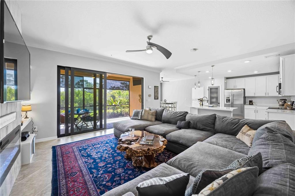 A living room with a large gray sectional, a live-edge coffee table, and sliding glass doors — 10055 CROOKED CREEK DRIVE UNIT 102, VENICE, FL