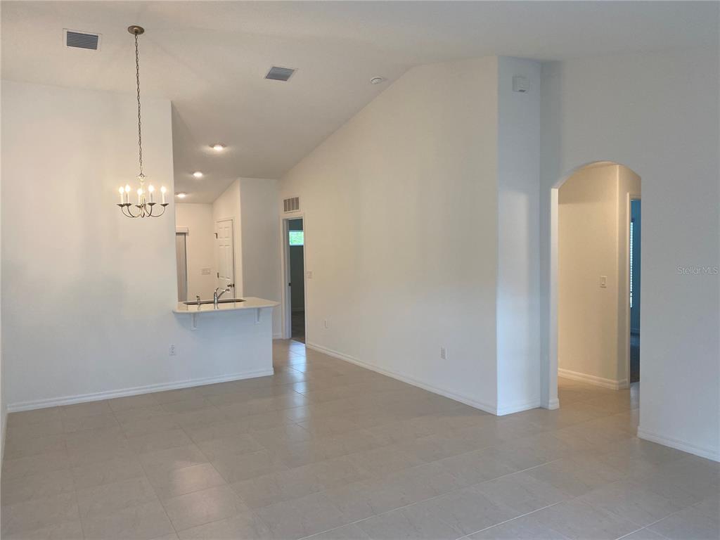 A bright, open-concept living area features white walls, tiled floors, and a kitchen breakfast bar — 2 RYAPPLE LANE UNIT A, PALM COAST, FL