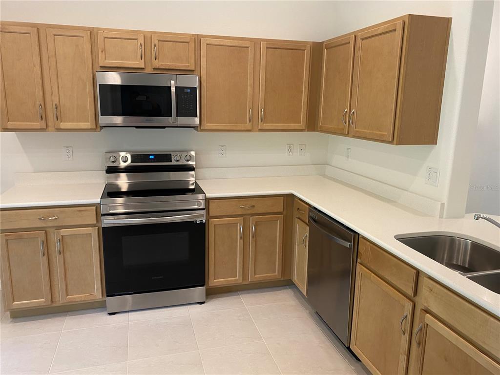A kitchen features light wood cabinets, stainless steel appliances, and white countertops — 2 RYAPPLE LANE UNIT A, PALM COAST, FL