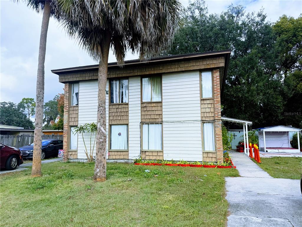 A two-story house with white siding, brown shingles, and a palm tree in the yard — 737 E CHURCH AVENUE, LONGWOOD, FL