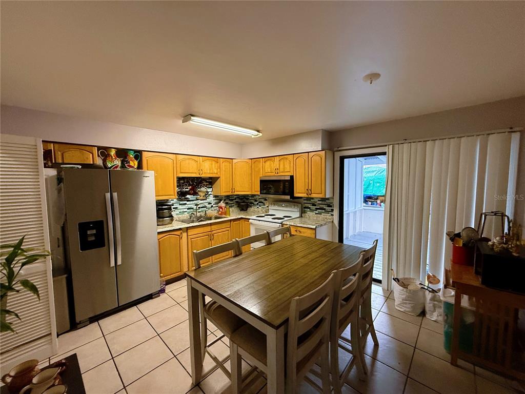 A kitchen features light wood cabinets, tile flooring, a dining table, and a sliding glass door — 737 E CHURCH AVENUE, LONGWOOD, FL