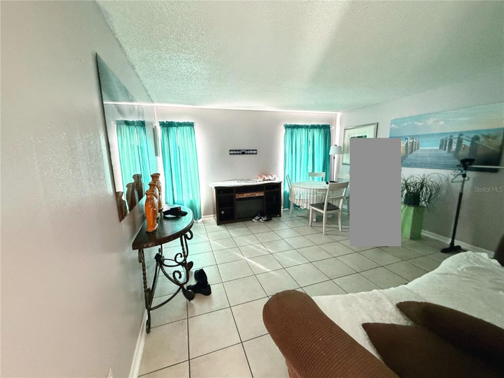 A living and dining area features tile flooring, teal curtains, and a dark wood console — 737 E CHURCH AVENUE, LONGWOOD, FL
