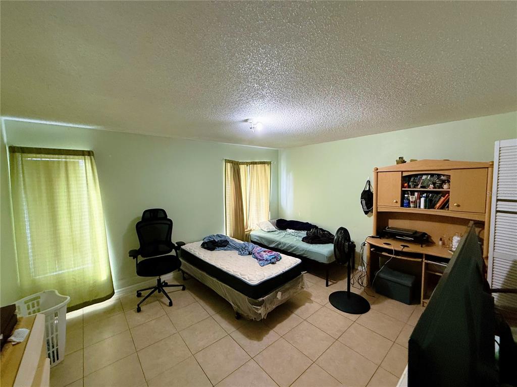A bedroom with tile flooring, two twin beds, a desk hutch, and green curtains — 737 E CHURCH AVENUE, LONGWOOD, FL