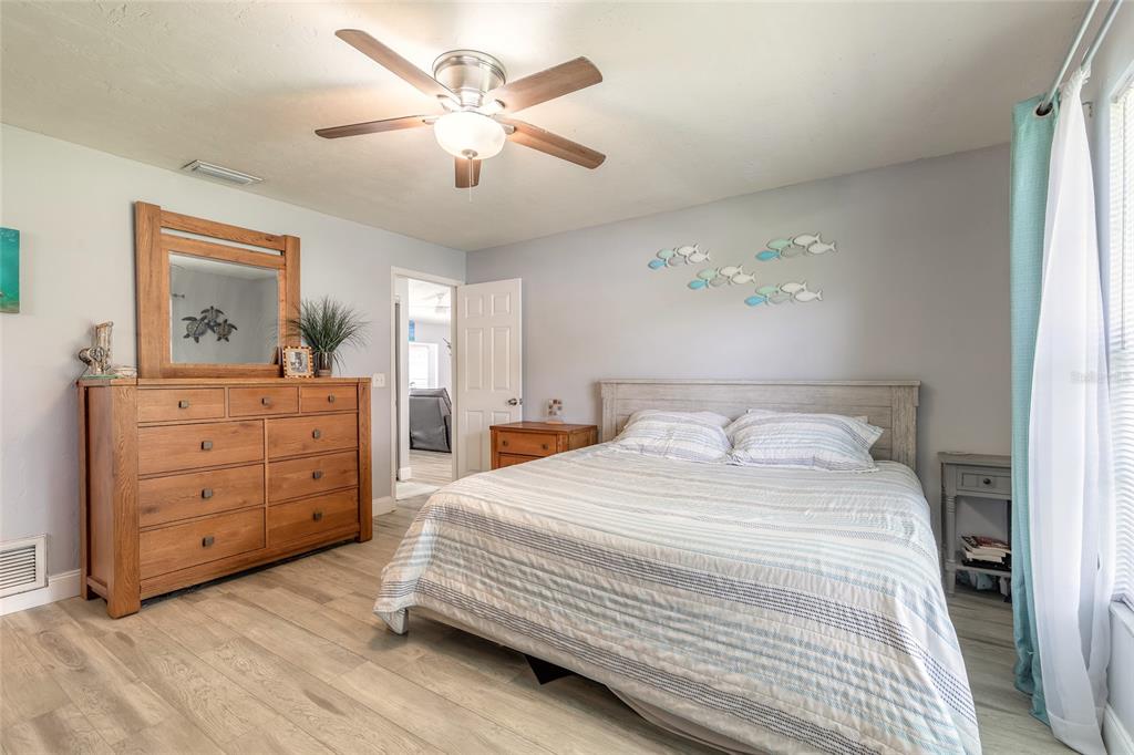 A bedroom features a wooden dresser with a mirror, a bed, and a ceiling fan — 2616 WOODLAND DRIVE, EDGEWATER, FL