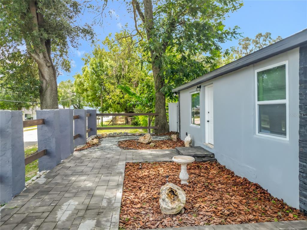 A paved walkway leads to a gray house exterior with a birdbath and mulch beds — 638 NW 6TH TERRACE, OCALA, FL