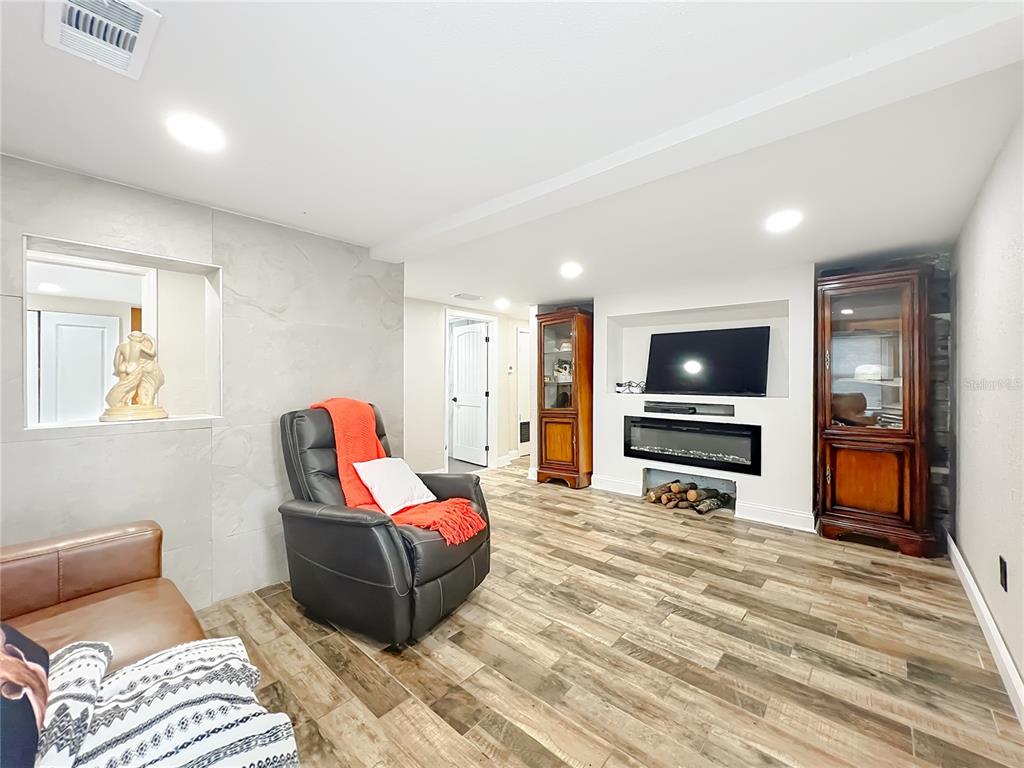 A living room features wood-look tile flooring, a fireplace, a television, and two wooden cabinets — 638 NW 6TH TERRACE, OCALA, FL