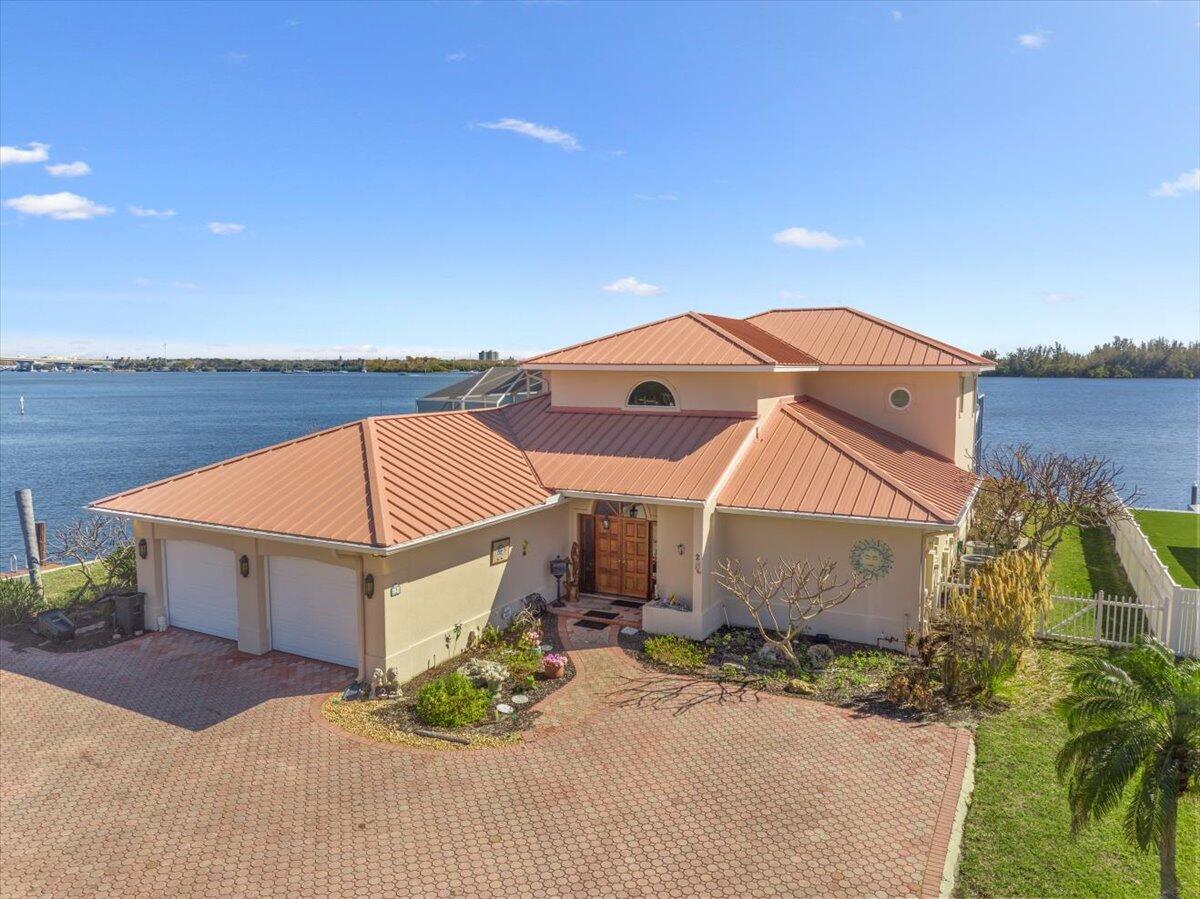 An aerial view of a waterfront house with a metal roof and brick paver driveway — 2 Seahorse Lane, Vero Beach FL 32960, VERO BEACH, FL