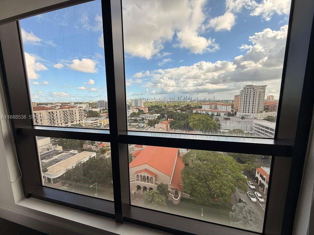 A view through a large window overlooking a city skyline, trees, and a church building — 2020 Ponce De Leon Blvd, Coral Gables FL 33134, CORAL GABLES, FL