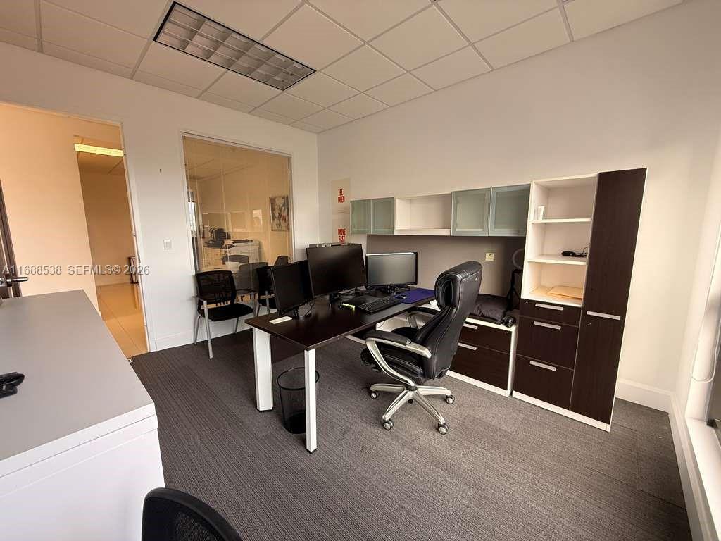 An office space features a dark wood desk, a rolling chair, and built-in storage cabinets — 2020 Ponce De Leon Blvd, Coral Gables FL 33134, CORAL GABLES, FL