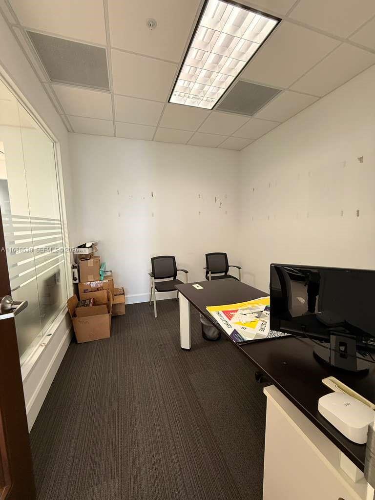 An office room features a desk, two chairs, cardboard boxes, and a glass wall partition — 2020 Ponce De Leon Blvd, Coral Gables FL 33134, CORAL GABLES, FL