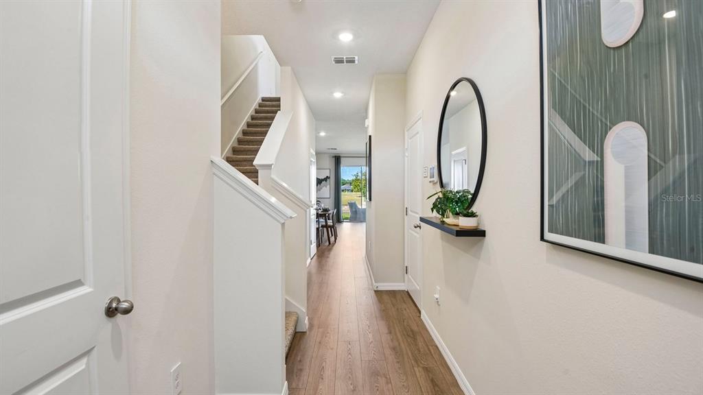 A hallway with wood-look flooring, a staircase, a wall mirror, and a view toward the back — 12603 CITRUS PARK LANE, TAMPA, FL