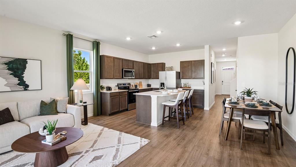 An open-concept living area features a kitchen with dark cabinets, an island, and dining space — 12603 CITRUS PARK LANE, TAMPA, FL
