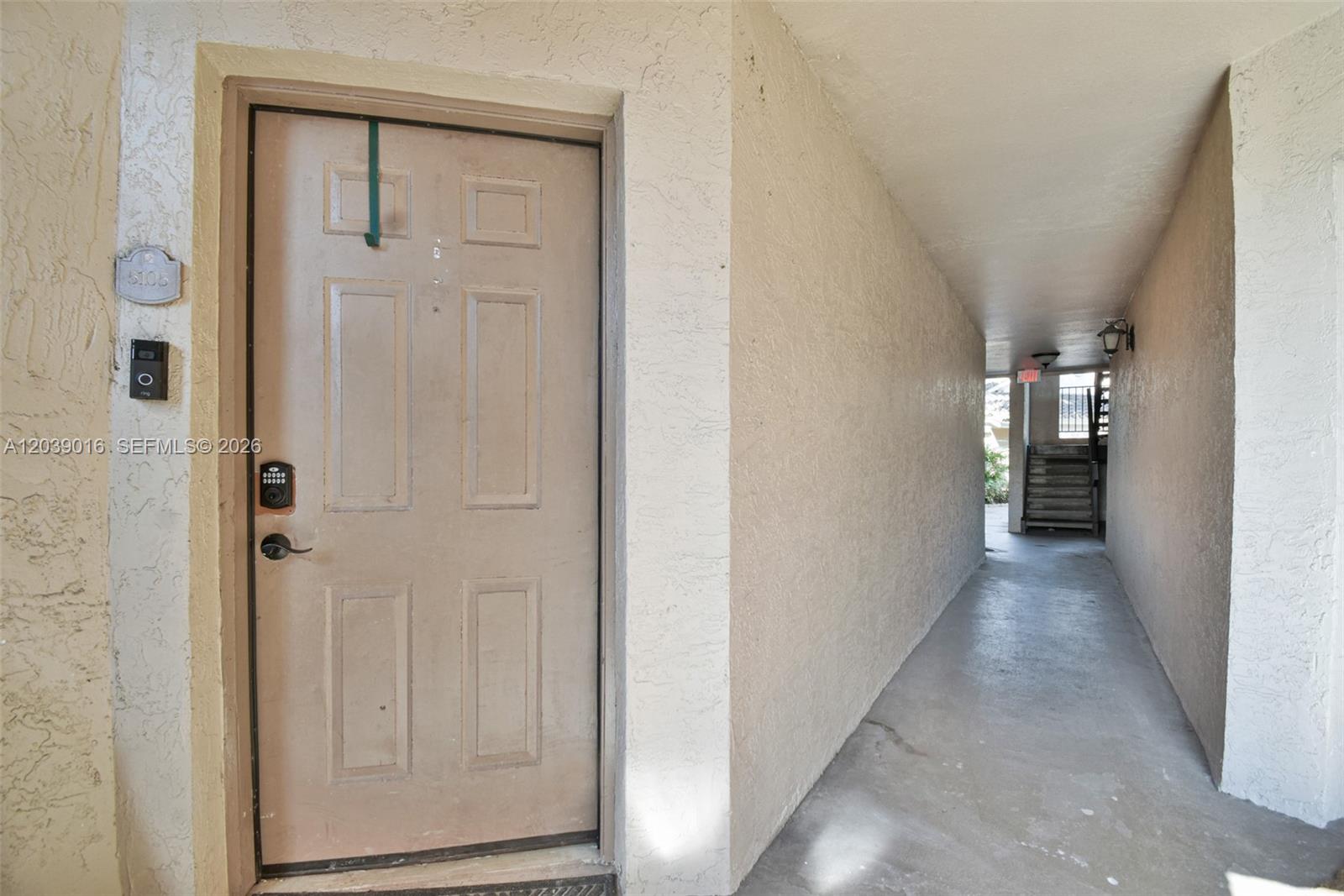 A beige door with a digital lock is situated in a concrete outdoor hallway — 2866 S University Dr # 5105, Davie FL 33328, DAVIE, FL