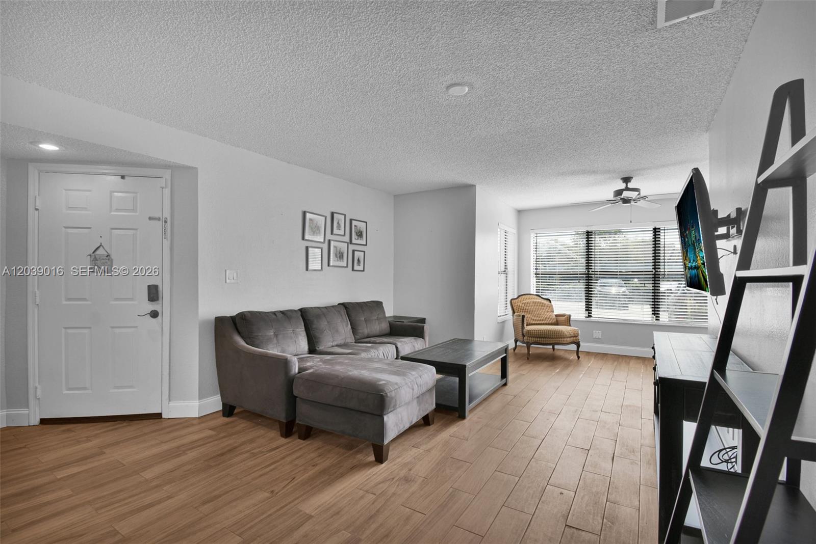 A living room features wood-look flooring, a gray sectional sofa, and a wall-mounted television — 2866 S University Dr # 5105, Davie FL 33328, DAVIE, FL