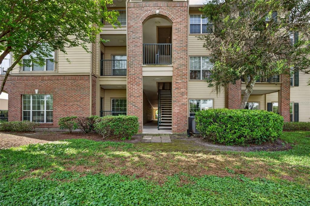 An exterior view of a multi-story apartment building with brick accents and a central staircase — 7800 POINT MEADOWS DRIVE UNIT 1338, JACKSONVILLE, FL