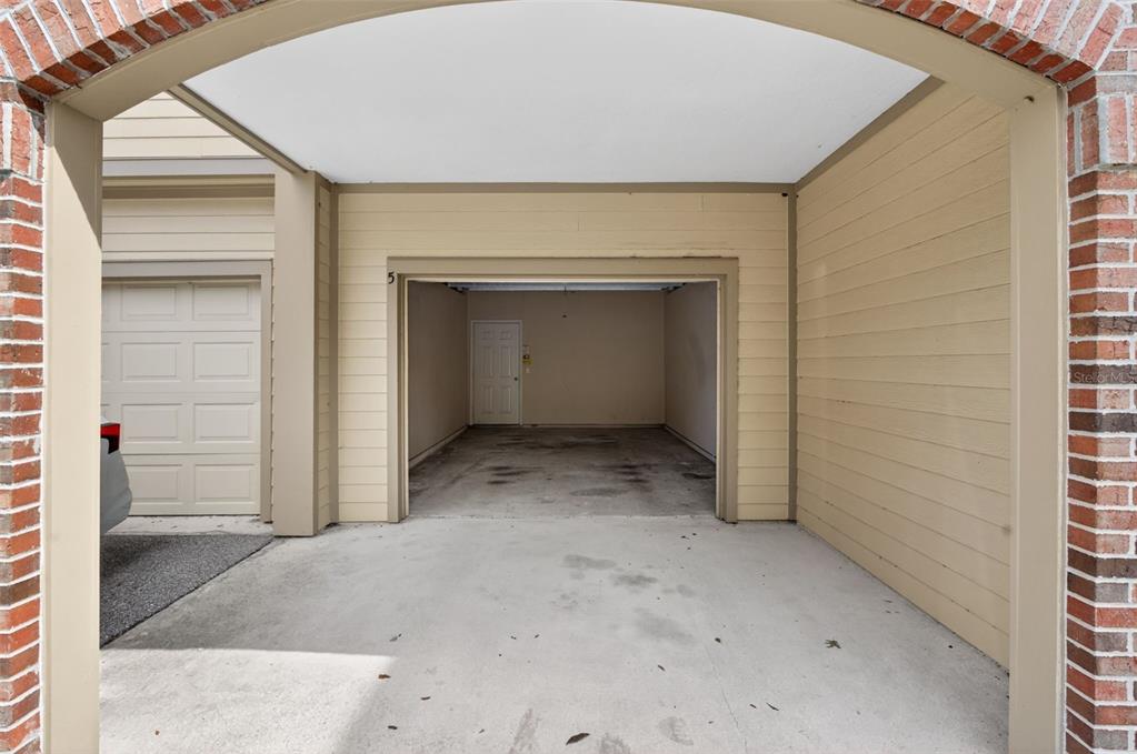 A covered carport area leads to an open garage bay with a white entry door — 7800 POINT MEADOWS DRIVE UNIT 1338, JACKSONVILLE, FL