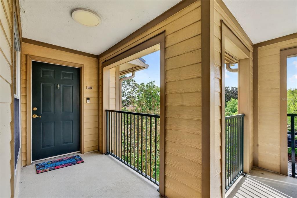 An exterior view of an apartment entryway with a dark door and a balcony railing — 7800 POINT MEADOWS DRIVE UNIT 1338, JACKSONVILLE, FL