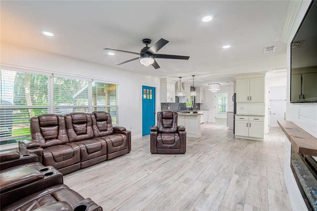 A living room with brown leather recliners, light wood-look flooring, and a bright blue door — 640 ORANGE VALLEY CIRCLE, LAKELAND, FL