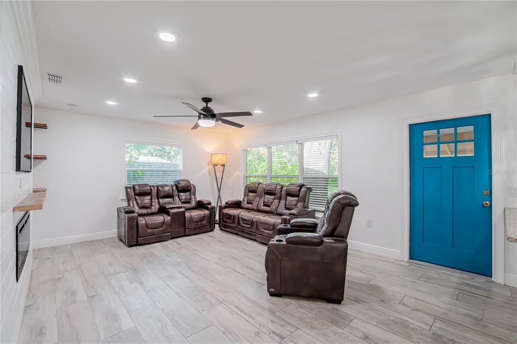 A living room features brown leather reclining furniture, light wood-look flooring, and a bright blue door — 640 ORANGE VALLEY CIRCLE, LAKELAND, FL