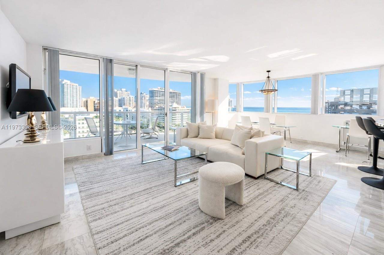 A bright living room features white furniture, a glass coffee table, and floor-to-ceiling windows — 3411 Indian Creek Dr, Miami Beach FL 33140, MIAMI BEACH, FL