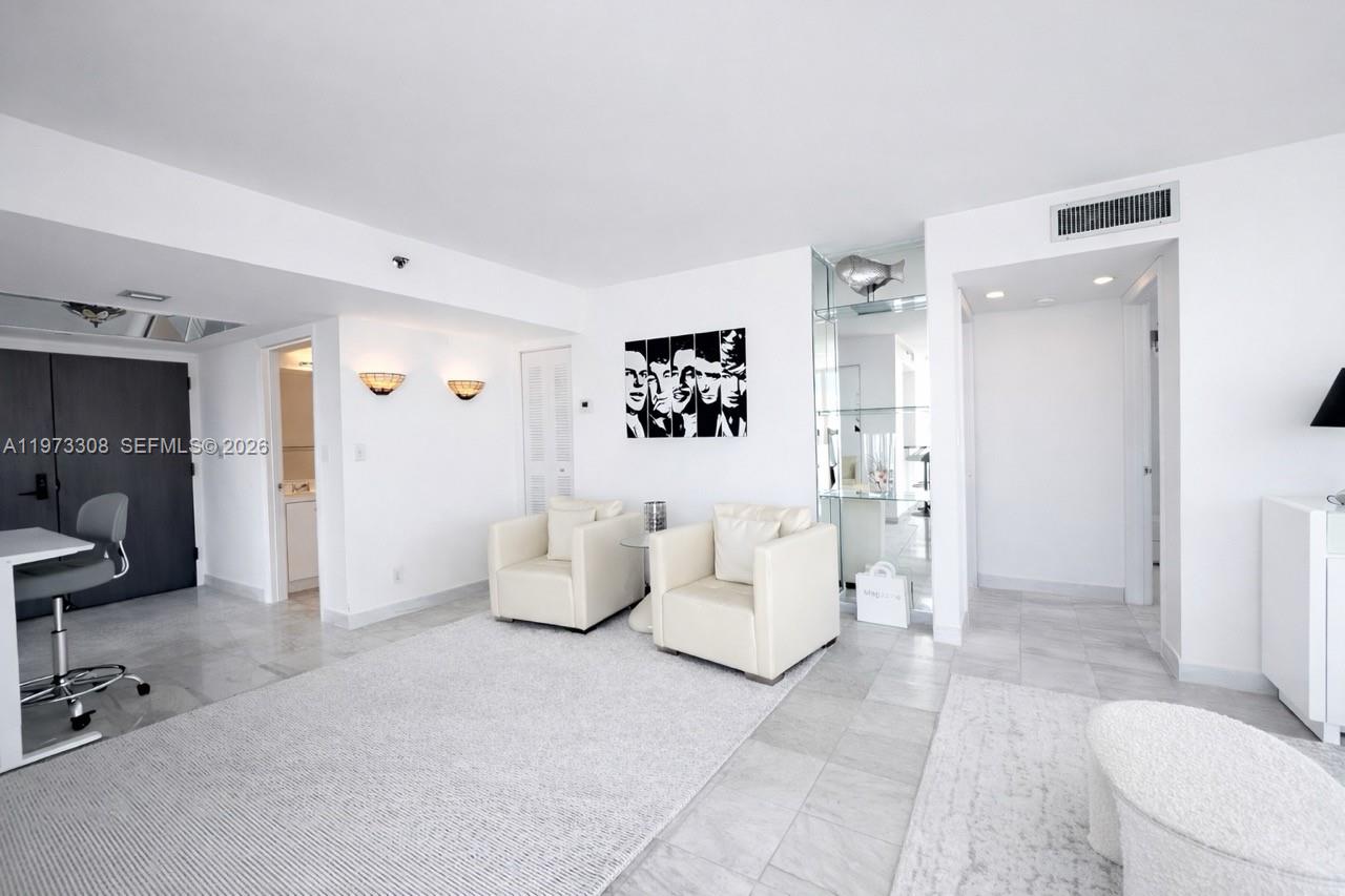 A bright living room features white walls, tiled floors, two cream armchairs, and wall art — 3411 Indian Creek Dr, Miami Beach FL 33140, MIAMI BEACH, FL